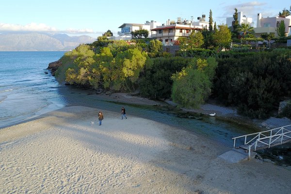 Μια παραλία που χωρίζεται από έναν ολόδεντρο λόφο με ένα ρέμα στην παραλία του Αλμυρού, στον Άγιο Νικόλαο.