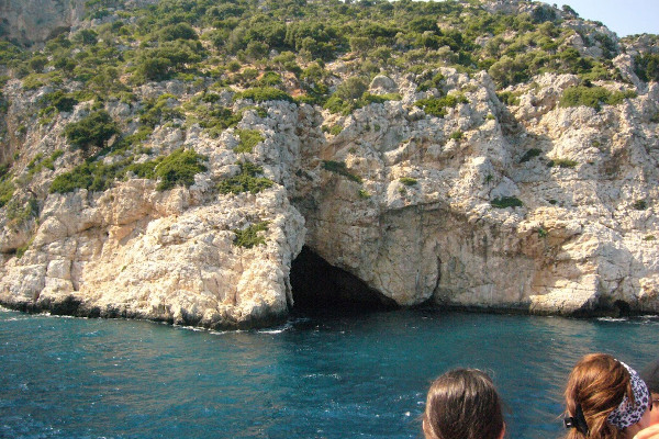 Τουρίστες βλέπουν το παράκτιο σπήλαιο των Κυκλώπων του νησιού Γιούρα κατά τη διάρκεια μιας περιήγησης με βάρκα.