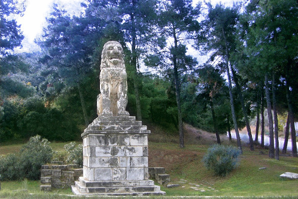Το μαρμάρινο άγαλμα της Αμφίπολης τοποθετημένο σε βάθρο που περιβάλλεται από την πλούσια βλάστηση της περιοχής.