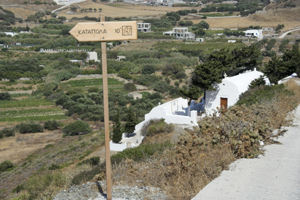 Μια ξύλινη πινακίδα που δείχνει την απόσταση σε χιλιόμετρα μέσα στο δίκτυο πεζοπορικών διαδρομών της Αμοργού.