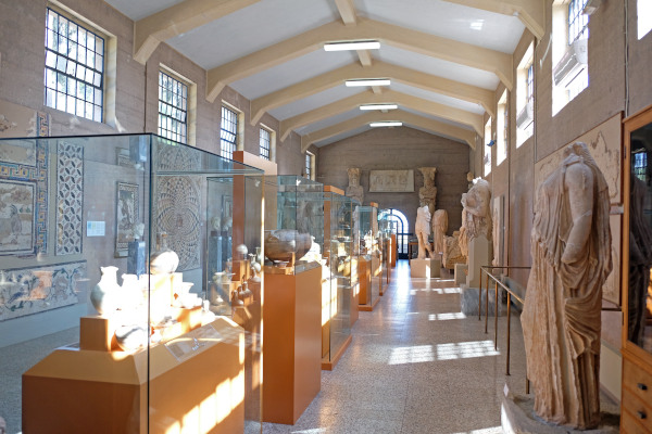 Φωτογραφία του διαδρόμου του Αρχαιολογικού Μουσείου Αρχαίας Κορίνθου με αγάλματα και εκθέματα .