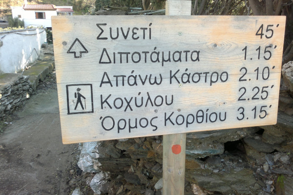 Μια ξύλινη πινακίδα που δείχνει την απόσταση σε λεπτά μεταξύ των πεζοπορικών προορισμών στο νησί της Άνδρου.