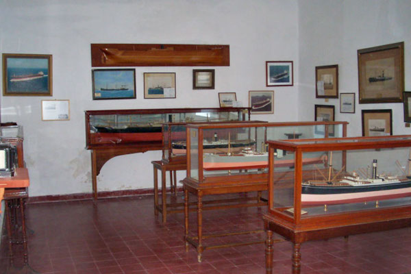 Μια εικόνα ενός από τα δωμάτια του Ναυτικού Μουσείου Άνδρου με θηκες και  εκθέματα που κρέμονται στον τοίχο.