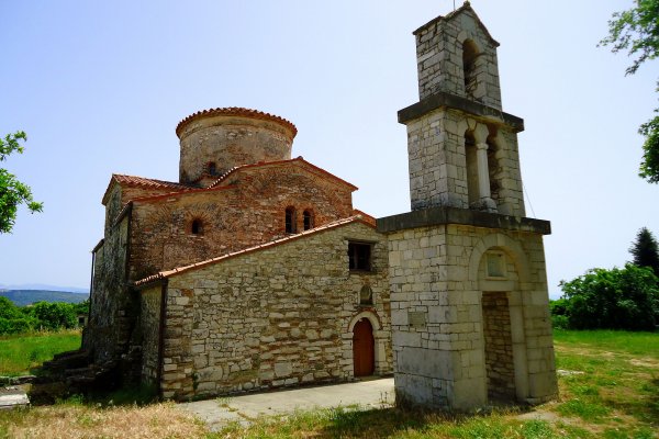 Η πετρόκτιστη βυζαντινή εκκλησία του Αγίου Δημητρίου με κεραμίδια σε έναν ανοιχτό χώρο.