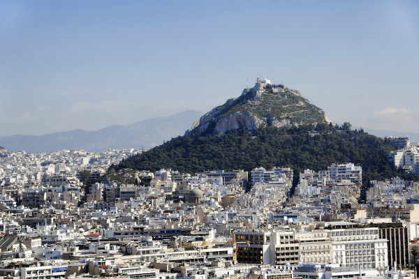 Πανοραμική θέα στο λόφο του Λυκαβηττού ανάμεσα στα κτίρια της πόλης της Αθήνας.