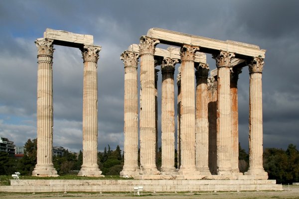 Πολλές κολώνες, μέρος του Ναού του Ολυμπίου Διός, σε ένα πάρκο με δέντρα.