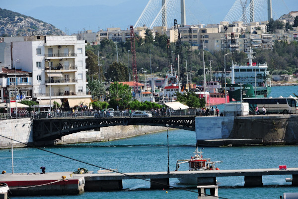 Φωτογραφία της παλιάς συρόμενης γέφυρας της Χαλκίδας με βάρκες και πολυκατοικίες στο βάθος.
