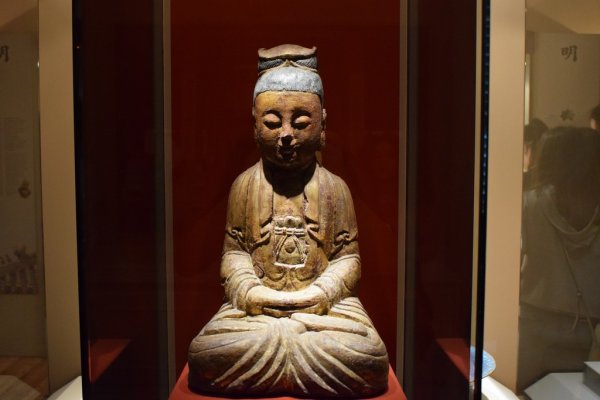 Ένα μικρό ασιατικό άγαλμα ενός ατόμου που κάθεται οκλαδόν στο Μουσείο Ασιατικής Τέχνης της Κέρκυρας.