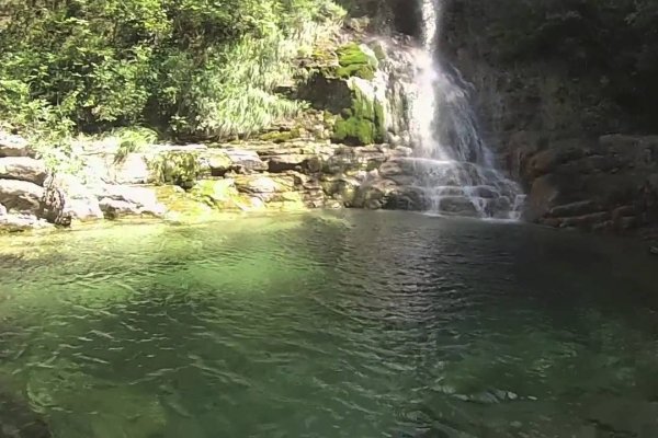 Ένας βράχος στον Ορλιά βρέχεται από νερό που πέφτει από ψηλά. Μια εικόνα με ζωντανό πράσινο μέσα και έξω από τα νερά.