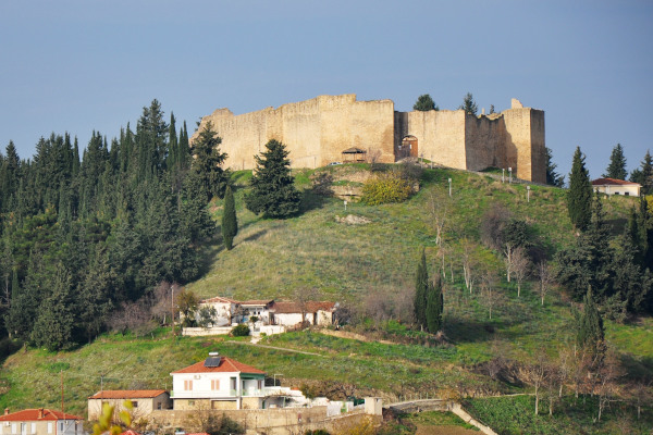 Μια εικόνα που δείχνει το Κάστρο του Φαναρίου στην κορυφή του λόφου με μερικά σπίτια του οικισμού κοντά σε αυτό.