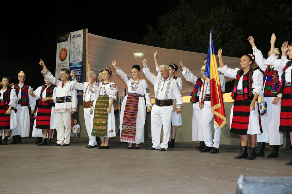 Μέλη ενός ρουμανικού πολιτιστικού συλλόγου φορώντας παραδοσιακά ρούχα χαιρετούν το κοινό από τη σκηνή.