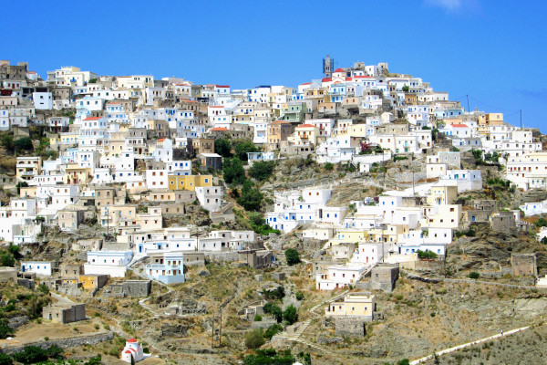 Μια επισκόπηση του χωριού Όλυμπος στην Κάρπαθο με λευκά και πολύχρωμα σπίτια σαν να κρέμονται από τον βράχο.