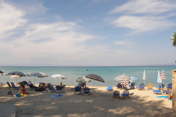 Κόσμος με ομπρέλες και ξαπλώστρες στην παραλία Χανιώτη στη Χαλκιδική.