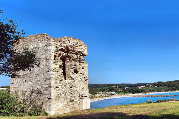 Τα απομεινάρια του πύργου Σταυρονικήτα με την αμμώδη παραλία και το γαλάζιο του ουρανού στο βάθος.