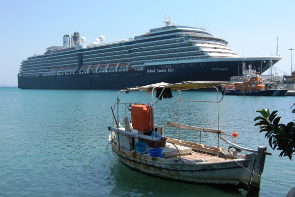 Ένα μεγάλο κρουαζιερόπλοιο ελλιμενισμένο στο λιμάνι του Κατακόλου καθώς ένα μικρό ψαροκάικο είναι αγκυροβολημένο στην ακτή του.