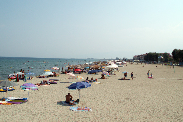 Φωτογραφία που δείχνει την παραλία της Ολυμπιακής Ακτής (Κατερινόσκαλα) με πολύ κόσμο να απολαμβάνει τον ήλιο και τη θάλασσα.