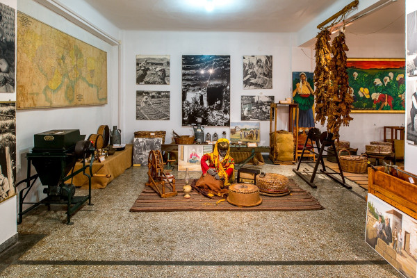Το εσωτερικό ενός από τους εκθεσιακούς χώρους του Μουσείου Καπνού Καβάλας με πολλά αντικείμενα και εικόνες στους τοίχους.