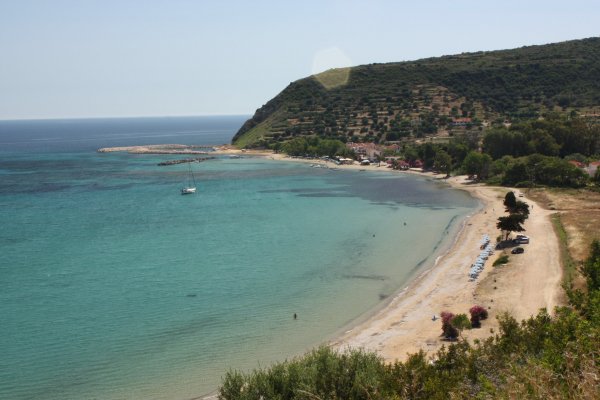 Η μεγάλη παραλία του Κατελειού με γαλαζοπράσινα νερά και ένα λόφο στο βάθος.