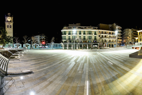 Η φωτισμένη πλατεία Νίκης της Κοζάνης κατά τη διάρκεια της νύχτας, με τον πύργο του ρολογιού ορατό στα αριστερά της εικόνας.