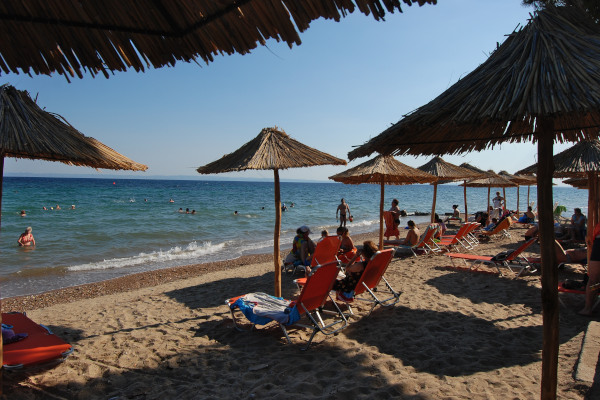 Μια φωτογραφία από την παραλία της Μεταμόρφωσης της Χαλκιδικής τραβηγμένη ανάμεσα στις ομπρέλες και τις ξαπλώστρες.