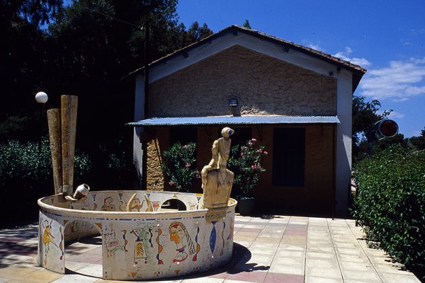 Ένας κυκλικός περιφραγμένος χώρος με σχέδια και ένα μικρό άγαλμα στην αυλή του Παιδικού Μουσείου Σταθμός Ναυπλίου.
