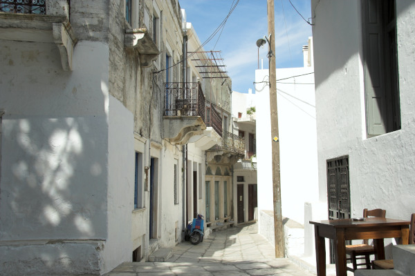 Ένας κεντρικός στενός δρόμος του χωριού Απείρανθος στη Νάξο με τα ολόλευκα κτίρια να το περιβάλλουν.