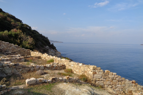 Τα ερείπια του αρχαιολογικού χώρου στα Σταγείρα με φόντο το βαθύ μπλε του Αιγαίου πελάγους.