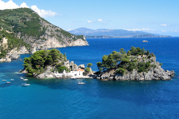 Μια φωτογραφία ενός μικρός νησιού με ένα παρεκκλήσι και δυο βράχους που περιβάλλεται από γαλάζια θάλασσα.