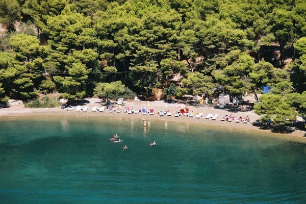 Αεροφωτογραφία της παραλίας Love Bay στον Πόρο και κόσμο να κολυμπά στα γαλαζοπράσινα νερά του.