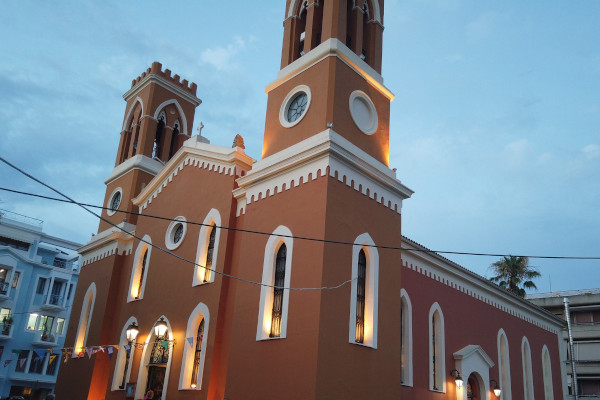 Η εκκλησία της Αγίας Κυριακής του Πύργου έχει έντονο πορφυρό χρώμα και λευκα κουφώματα, και δύο καμπαναριά.