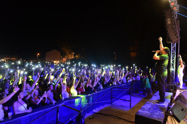 Μια φωτογραφία που δείχνει μέλη μιας μπάντας στη σκηνή και πλήθος κόσμου στο κοινό.