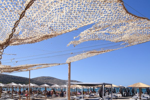 Ένα beach bar στην παραλία της Αναβύσσου με δεκάδες ομπρέλες και ξαπλώστρες κάτω από το γαλάζιο του ουρανού.