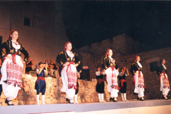 Μια μπάντα και χορευτές με παραδοσιακά ρούχα χορεύουν κατά τη διάρκεια μιας παράστασης του καλοκαιρινού φεστιβάλ.