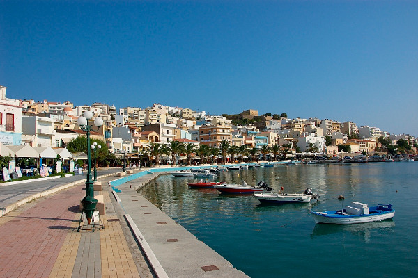 Η πεζοδρομημένη παραλιακή της Σητείας στην Κρήτη με λευκά κτίρια στα αριστερά και γαλάζια θάλασσα στα δεξιά.