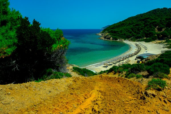 Φωτογραφία τραβηγμένη από λόφο στην παραλία του Άγκιστρου μεταξύ καταπράσινων λόφων και πράσινης θάλασσας.