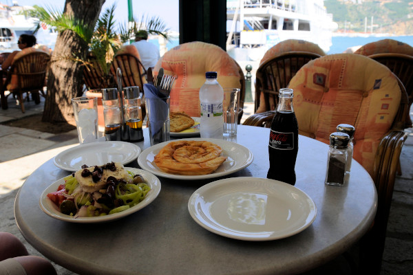 Εικόνα με ελληνική σαλάτα και Σκοπελίτικη τυρόπιτα σε εστιατόριο μπροστά από το λιμάνι.