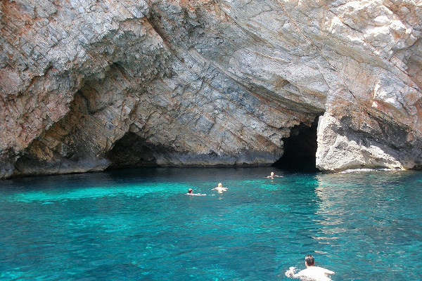 Άνθρωποι που κολυμπούν στα κρυστάλλινα νερά μπροστά από τις θαλάσσιες σπηλιές Πεντεκάλη και Διατρυπτή στη Σκύρο.