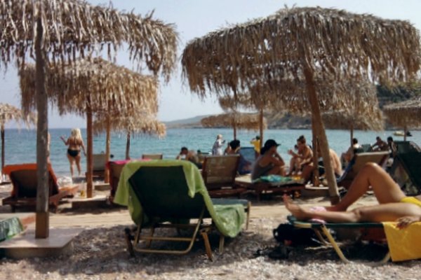 Άνθρωποι σε ξαπλώστρες και ομπρέλες στην παραλία της Αγίας Μαρίνας (Παράδεισος) των Σπετσών.