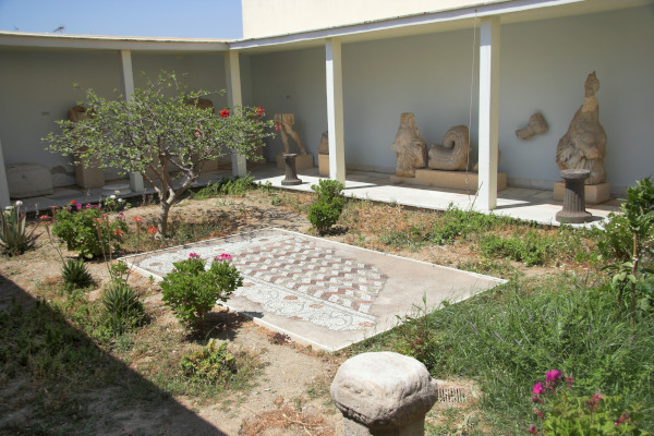 Η εσωτερική αυλή του Αρχαιολογικού Μουσείου Τήνου με γλυπτά μπροστά στους τοίχους.