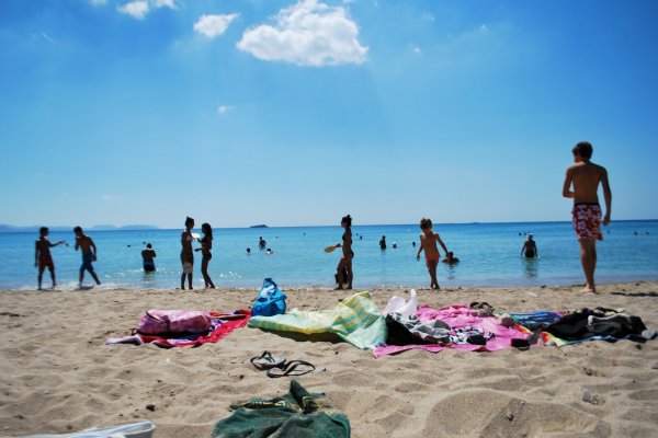 Κόσμος που απολαμβάνει τον ήλιο, την άμμο και τον καλό καιρό στην παραλία της Βάρκιζας στην Αττική.