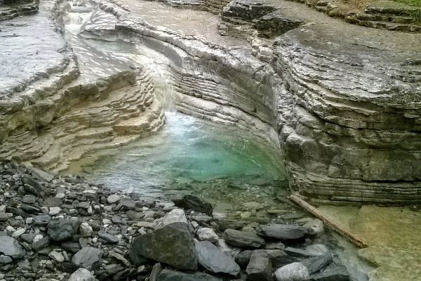 Το νερό του ρέματος Ρόγκοβο που ρέει μέσα από τους βράχους και δημιούργησε τη φυσική κολυμπήθρα.